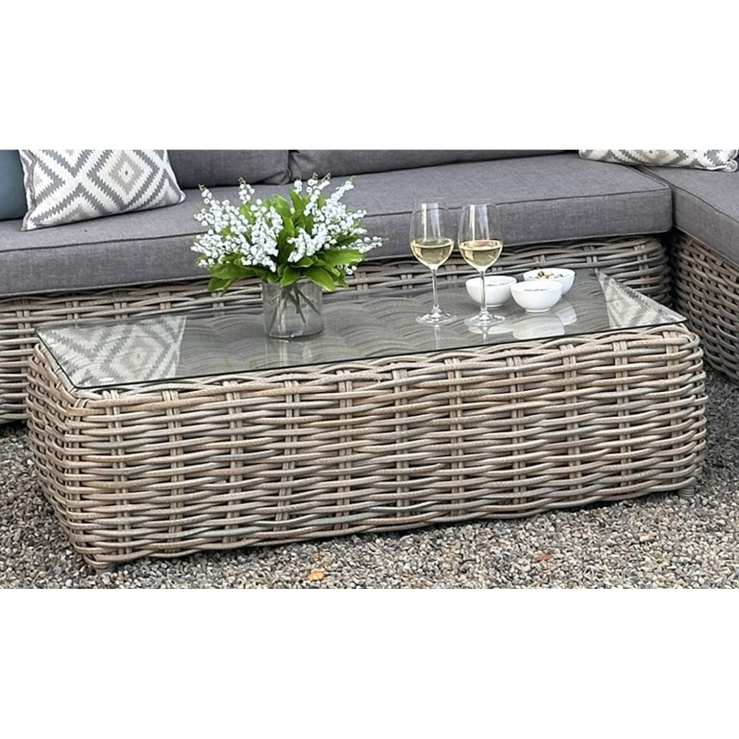 Hill Interiors Amalfi Collection beige outdoor large corner set with glass table in a modern garden setting
