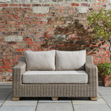 Hill Interiors Capri Collection beige outdoor two seater sofa in a modern garden setting