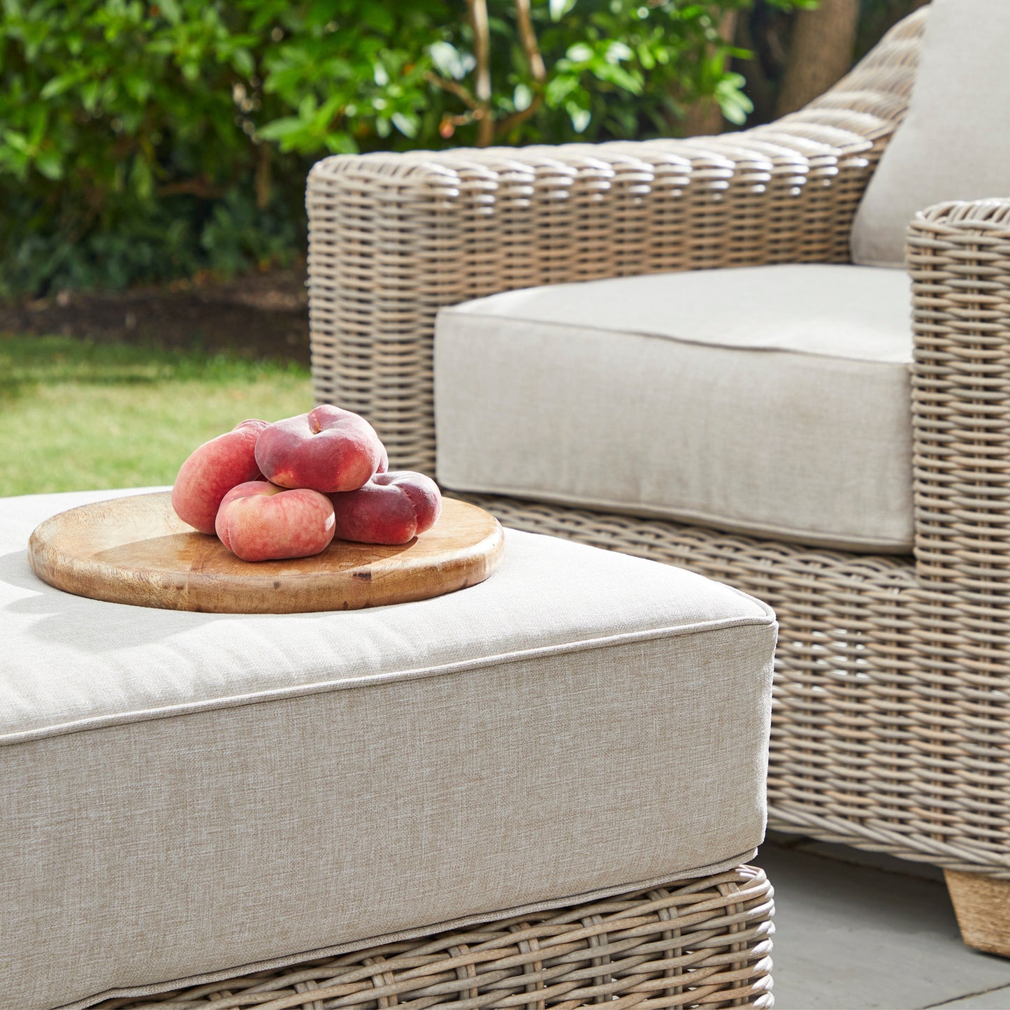 Side view of Hill Interiors Capri outdoor foot stool showing the beige fabric and metal frame