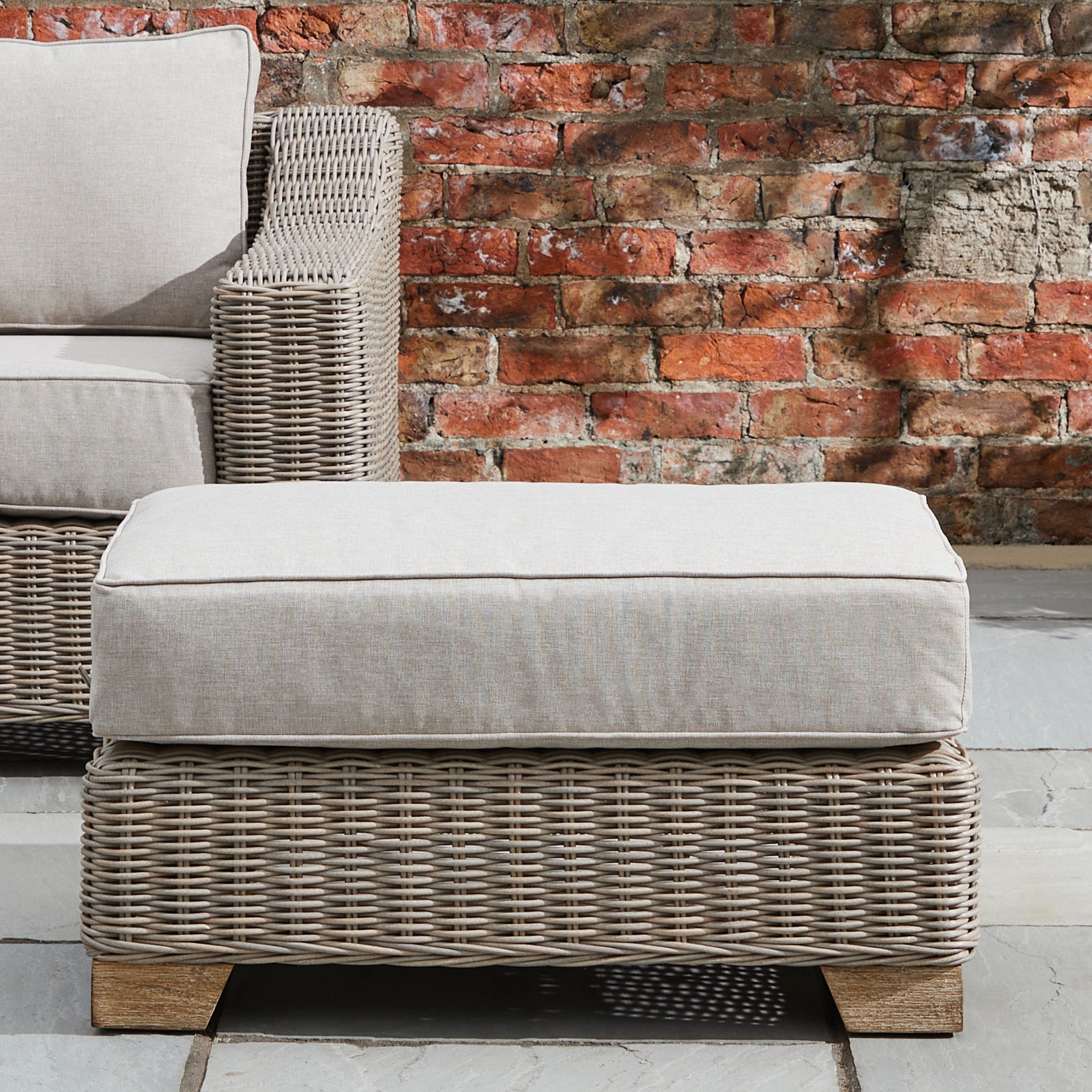 Hill Interiors Capri Collection beige outdoor foot stool in a modern garden setting