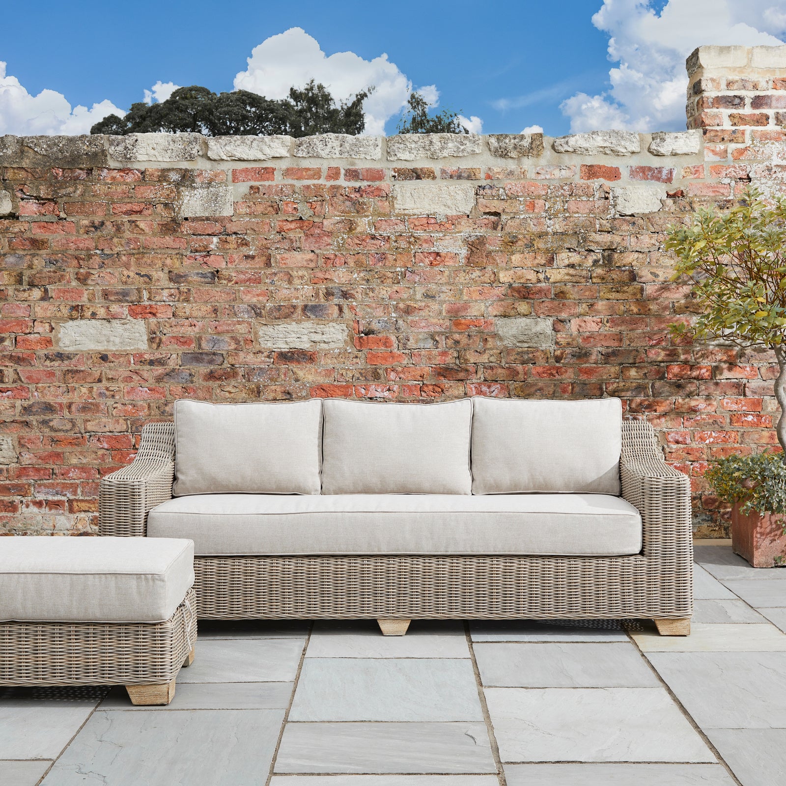 Side view of Hill Interiors Capri outdoor three seater sofa showing the beige fabric and metal frame
