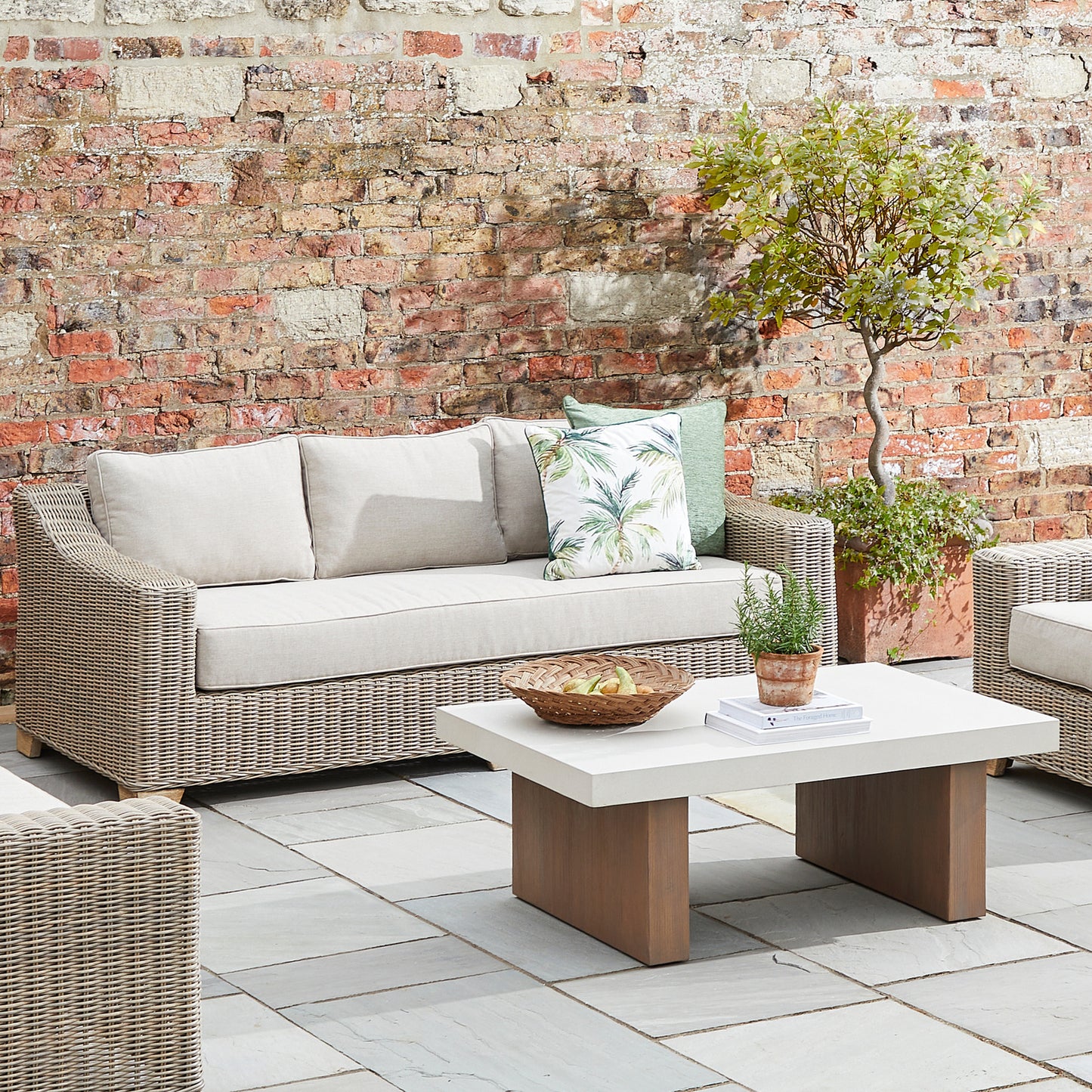 Hill Interiors Capri Collection beige outdoor three seater sofa in a modern garden setting