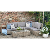 Hill Interiors Amalfi Collection beige outdoor large corner set with glass table in a modern garden setting