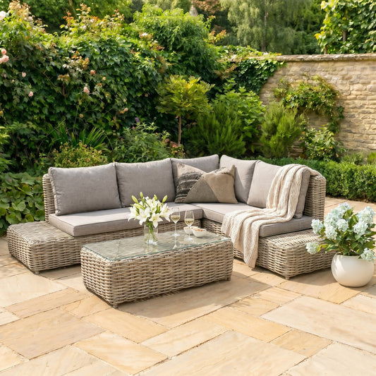 Hill Interiors Amalfi Collection beige outdoor large corner set with glass table in a modern garden setting