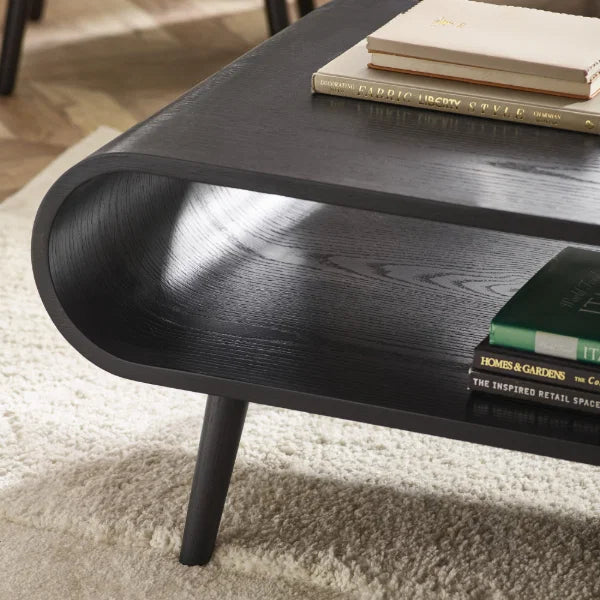 	Apollo black ash coffee table with curved silhouette in a modern Scandinavian living room setting
