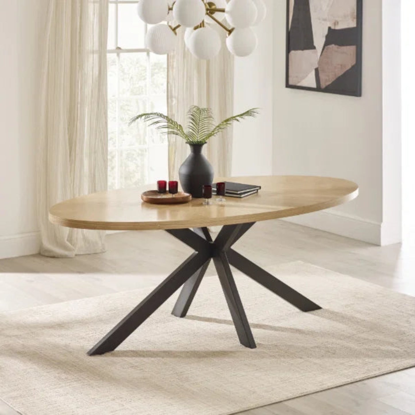 Bondi oval dining table with surfboard-shaped light oak top and black legs in a modern dining setting
