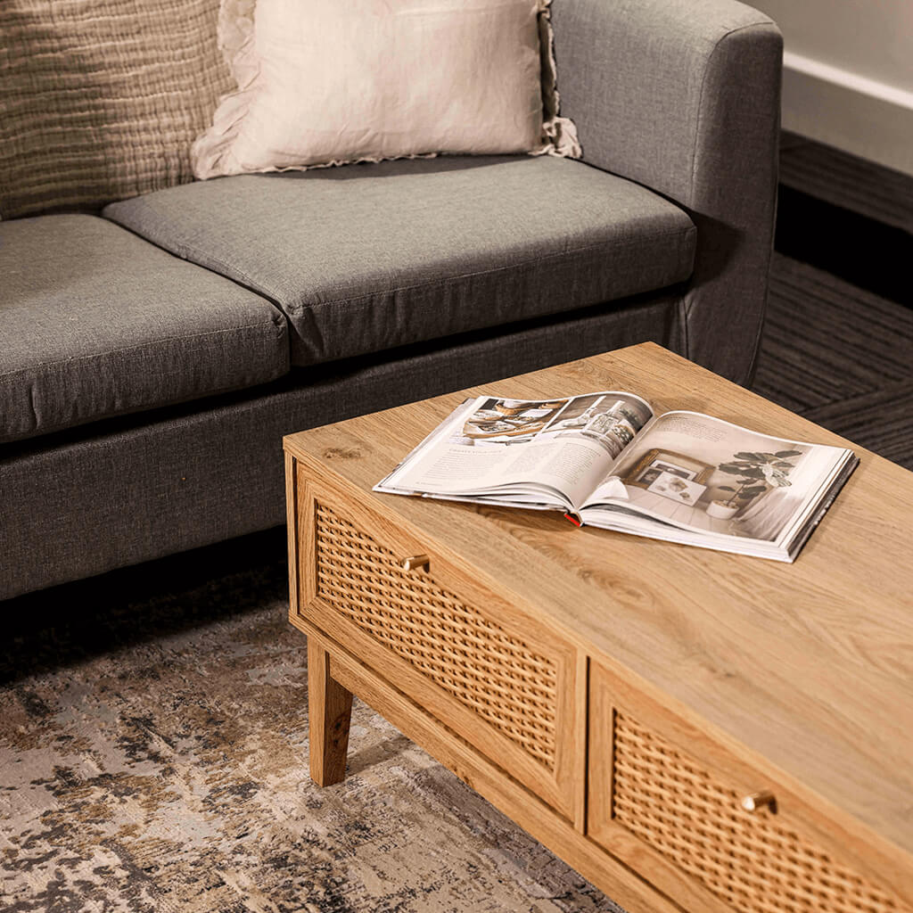 LPD Furniture Bordeaux oak coffee table with rattan front and gold fittings in a modern living room setting