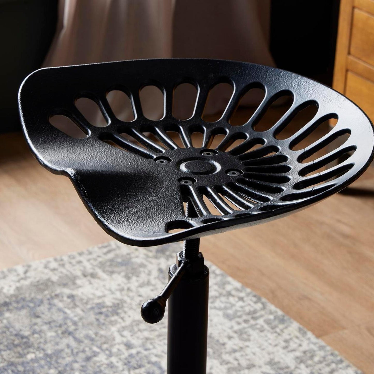 Close-up of Hill Interiors adjustable tractor seat stool showcasing the tractor-style seat design and black metal finish