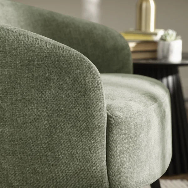 Dahlia olive green accent chair with curved backrest in a modern living room setting