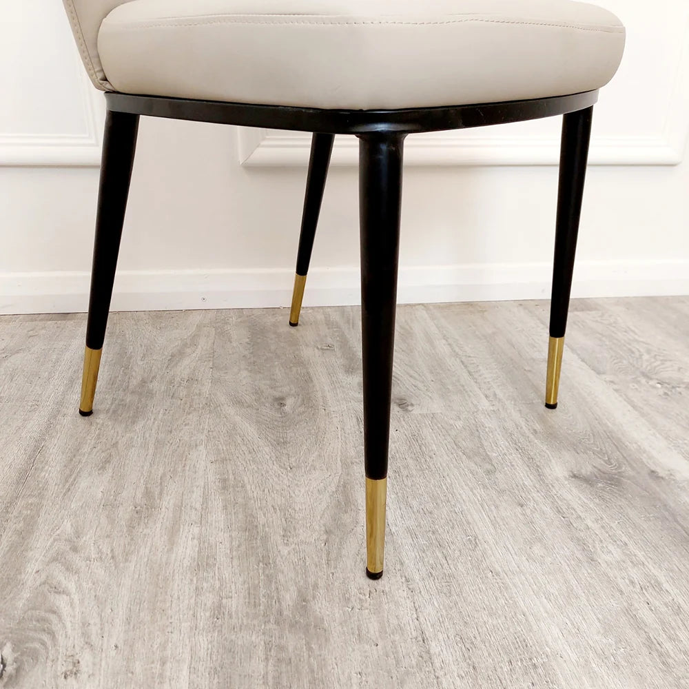 Furnish365 Etta dining chair in soft neutral fabric with curved backrest and gold-tipped legs in a contemporary dining setting