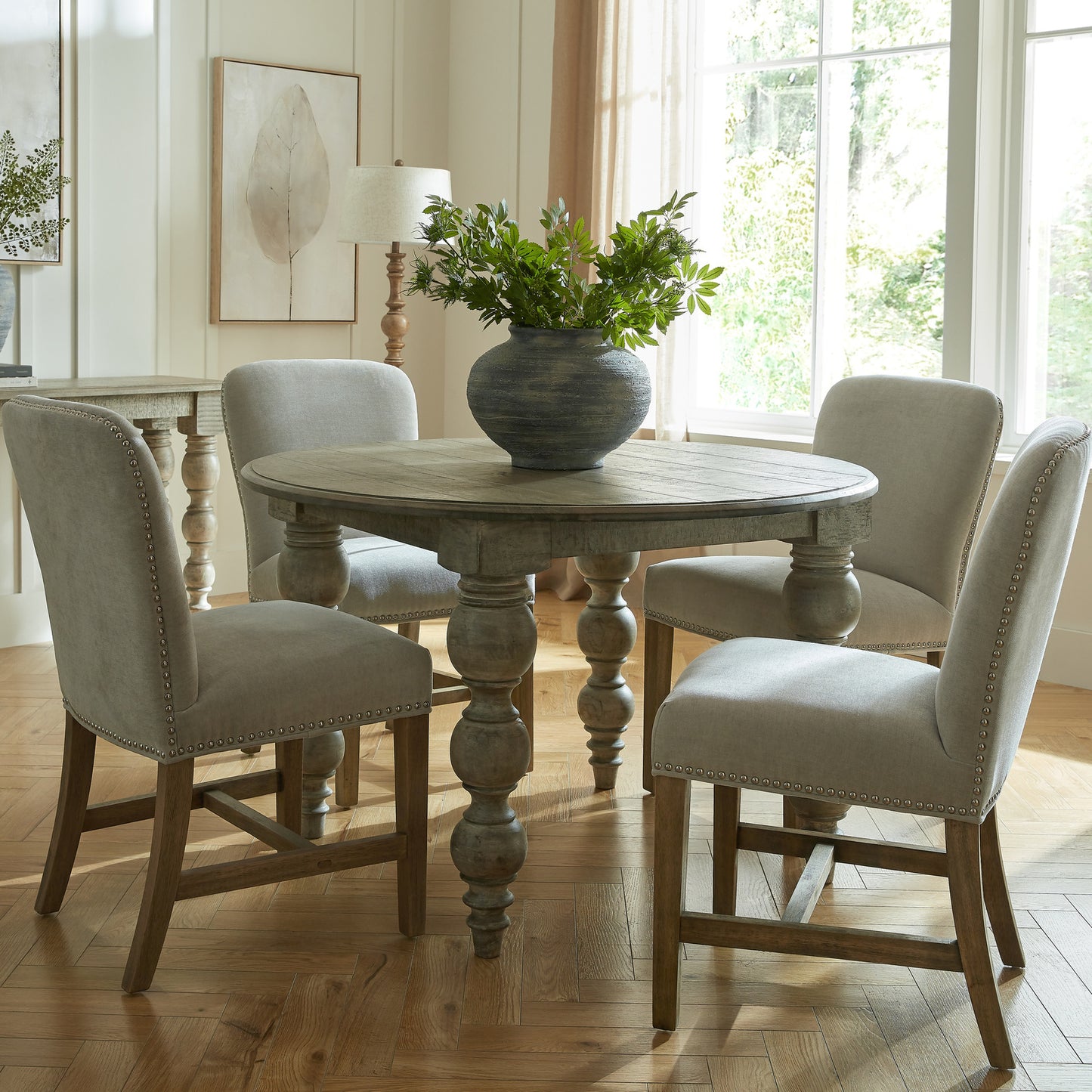 	Hill Interiors Cobham grey dining chair with antique brass stud detailing and weathered oak frame, placed in a classic dining setting