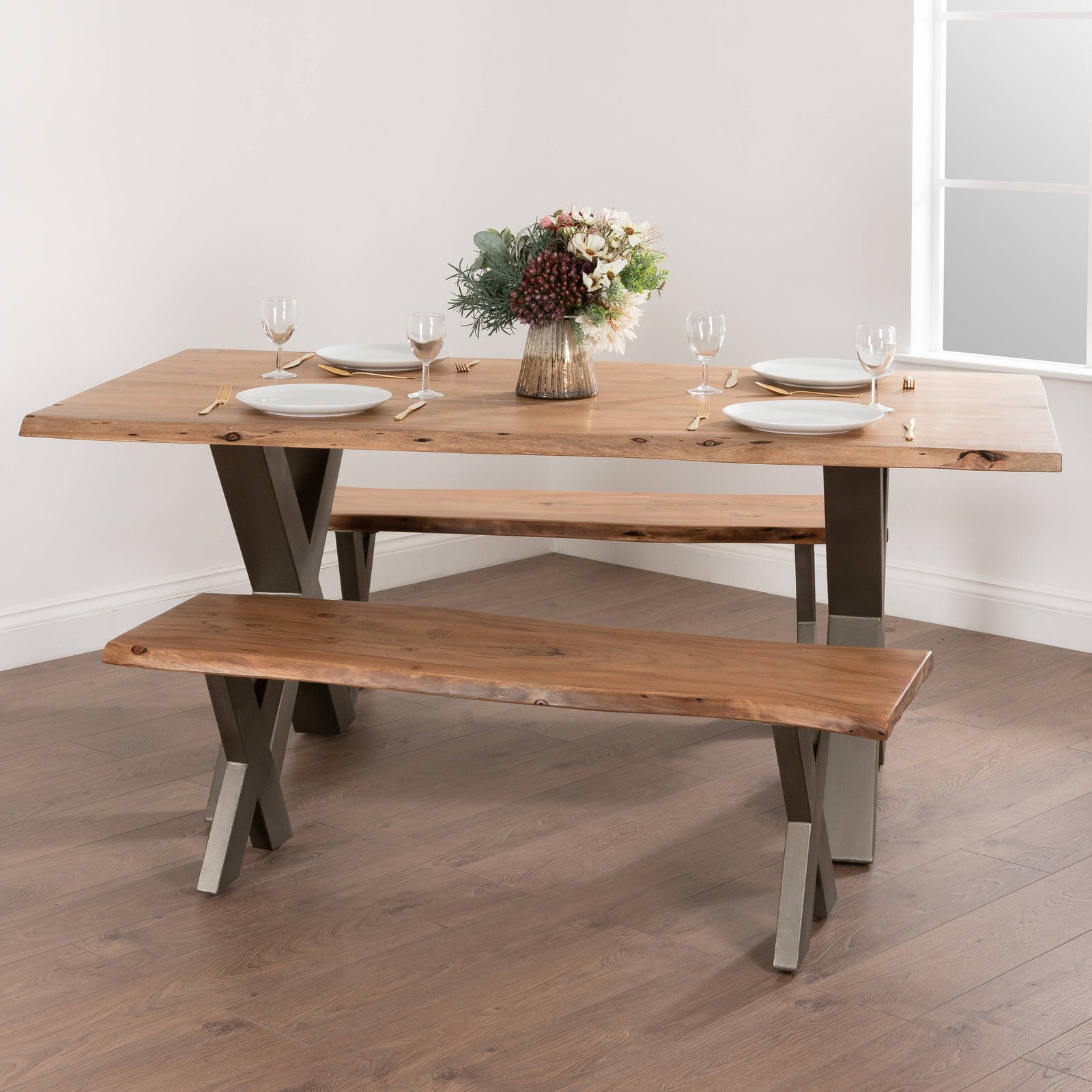 Hill Interiors Live Edge Collection acacia wood bench with grey metal cross-leg frame, placed in a modern dining setting