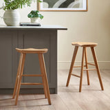 	Mulu natural oak bar stool with saddle seat in a modern kitchen setting