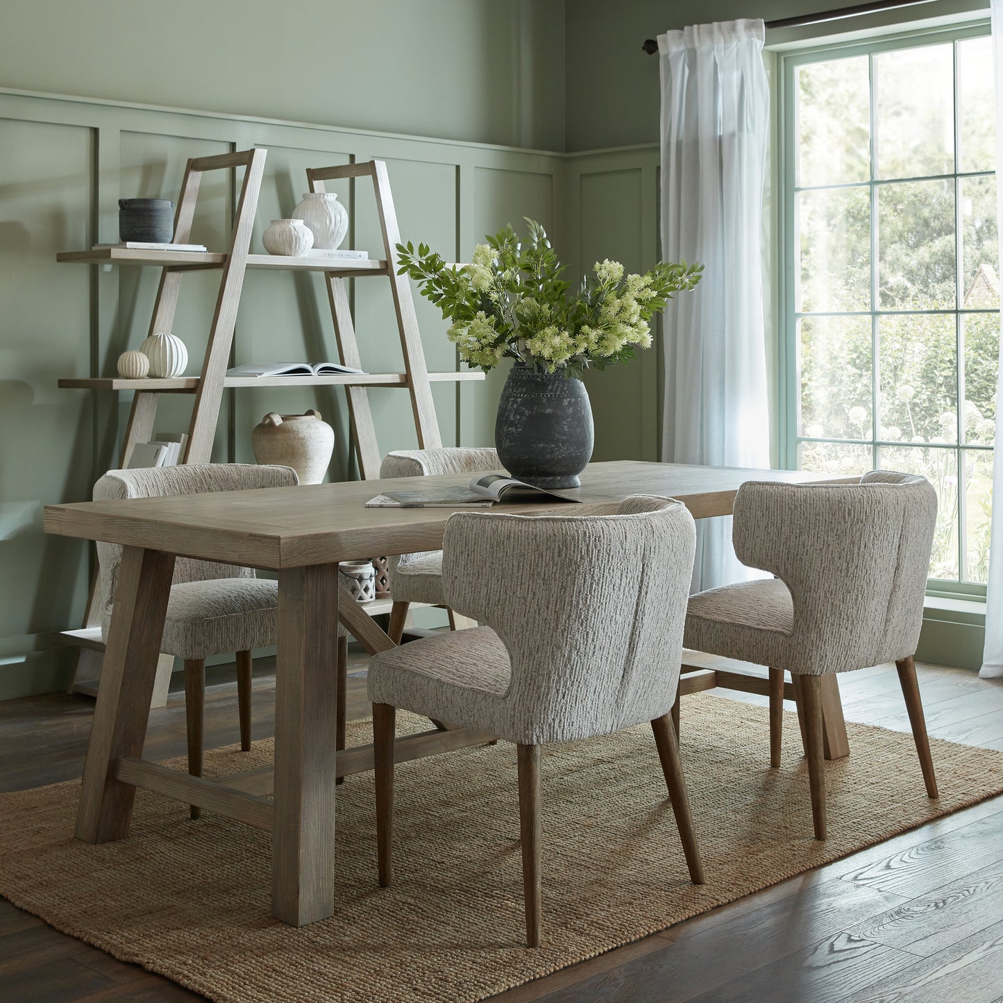 Side view of Hill Interiors Avia mist grey dining chair showing the fabric upholstery and wooden frame