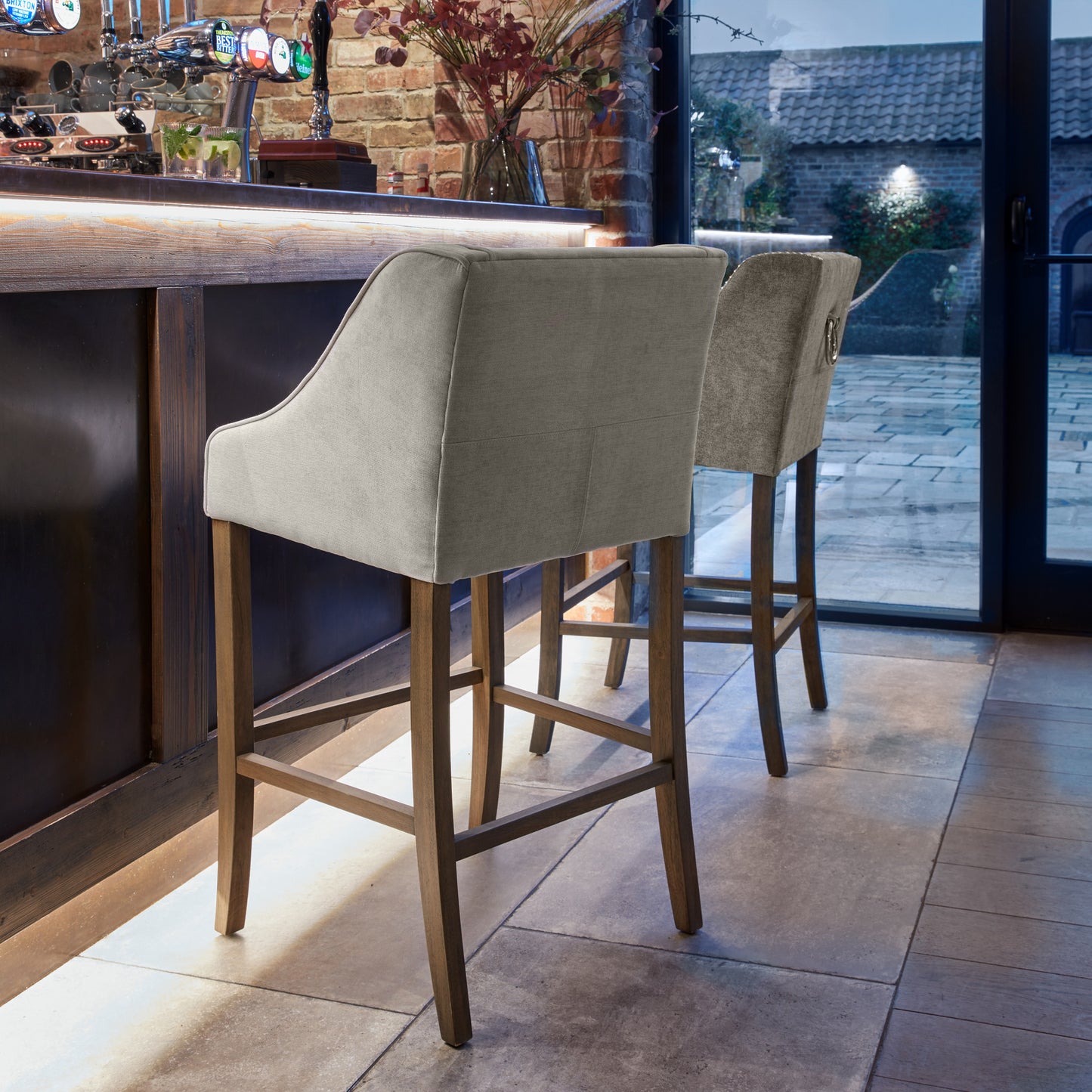 Side view of Hill Interiors Epsom grey barstool showing the fabric upholstery and wooden frame
